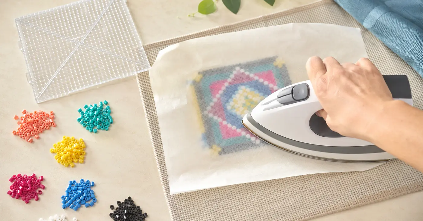 Adult safely ironing a colorful fuse bead design through translucent ironing paper on a heat-safe mat